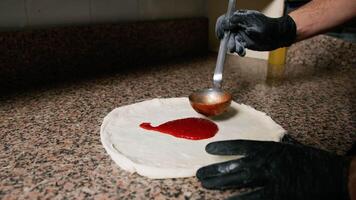 Pizza cocinero agregando el tomate salsa en masa antes de horneando eso video