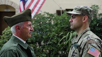 Soldier And Father Veteran Look At Each Other At The American Military Flag video