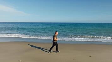 nadenkend Mens rennen sport Aan de zanderig strand in de buurt oceaan video