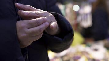 Close up of an old woman trying to put on a ring on her finger. Art. Elderly female in a warm coat trying on a ring. video