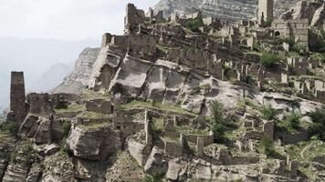 Aerial view of an ancient abandoned stone village with ruined buildings. Action. Rock cliff with old towers and constructions on a sunny day, concept of archeology. video