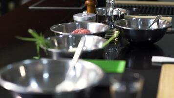 Table view with different ingredients in bowls. Art. Close up of metal deep plates with flour, potato, green onion near a wooden cutting board, concept of cooking food. video