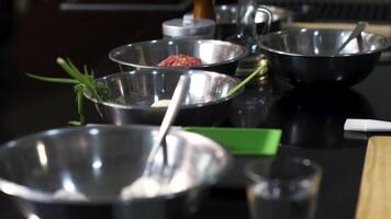 Table view with different ingredients in bowls. Art. Close up of metal deep plates with flour, potato, green onion near a wooden cutting board, concept of cooking food. video