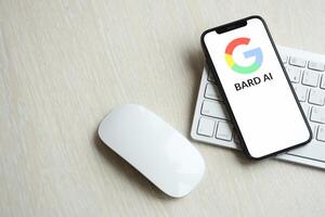 KYIV, UKRAINE - MARCH 17, 2024 Google Bard logo on iPhone display screen with apple keyboard and mouse on table photo