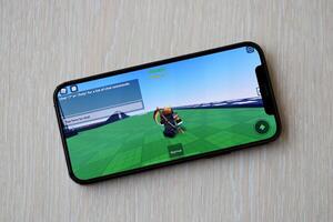 Roblox mobile iOS game on iPhone 15 smartphone screen on wooden table during mobile gameplay photo