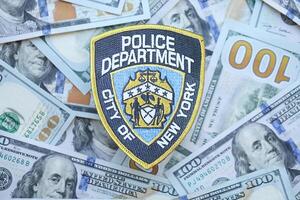 KYIV, UKRAINE - MARCH 9, 2024 US NYPD Police patch on many US hundred dollar bills photo