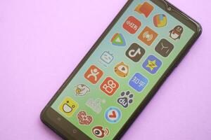 KYIV, UKRAINE - APRIL 1, 2024 Asian apps icon on smartphone screen on purple table photo