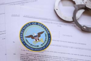 KYIV, UKRAINE - MARCH 9, 2024 US Department of Defense seal with handcuffs on many US District Court warrants and complaints photo