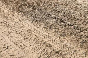 Wheel track on mud. Traces of a tractor or heavy off-road car on brown mud in wet meadow photo