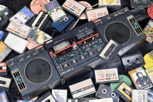 KYIV, UKRAINE - 4 MAY, 2023 Audio cassettes stacked and placed around obsolete record player photo