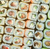 Close-up of a lot of sushi rolls with different fillings. Macro shot of cooked classic Japanese food. Background image photo