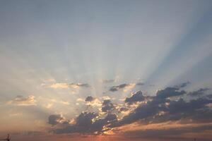 Beautiful sunrise with warm orange sunlight and beams through blue sky photo