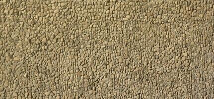 Texture of a stone wall with small round pebble stones. Part of a stone wall as a background or texture photo