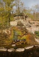 Beautiful waterfall between large rocks in autumn forest. Sofievskiy park in Uman, Ukraine photo