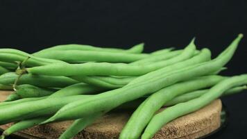 close up of green beans on rotating display, black background. video