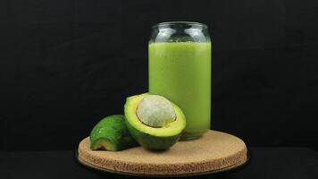 Rotating display of avocado juice on black background. video