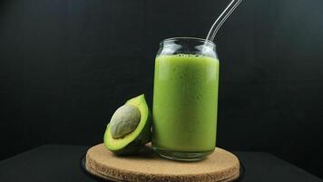 Rotating display of avocado juice on black background. video