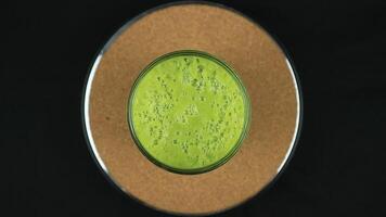 Top View Rotating display of avocado juice on black background. video