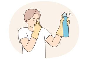 Dissatisfied man with spray to remove unpleasant odors covers nose with hand spraying freshener vector