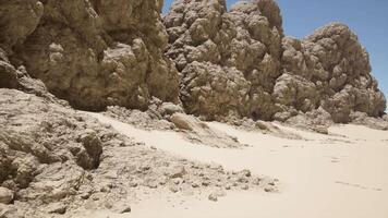 un arenoso playa cubierto en un montón de rocas video