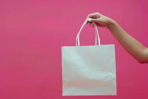 AI generated Female hand holding white shopping bag on pink background. Discount sale concept. photo