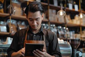 Asian man barista checks orders on tablet in cafe. photo