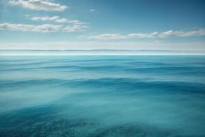 blue ocean with clouds and sun in the sky photo