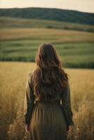 a woman with long hair standing in a field photo