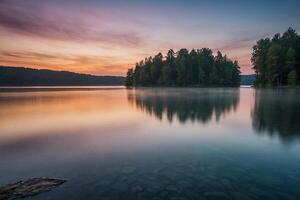 a lake with trees and a foggy sky at sunset photo