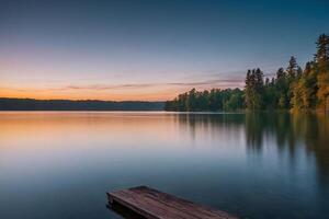 un lago con arboles y un brumoso cielo a puesta de sol foto