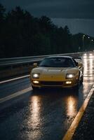 a sports car driving down a wet road at night photo