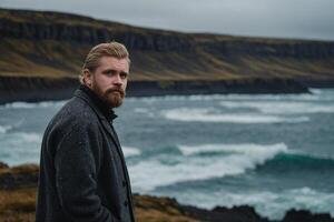 a man with a beard standing near the ocean photo