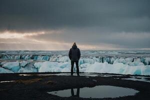 man standing on the edge of a glacier photo