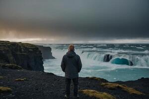 man standing on the edge of the cliff looking at the ocean photo