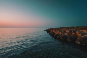 a rocky shoreline with water and sky at sunset photo