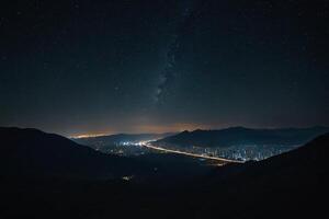 the night sky over a city and mountains photo