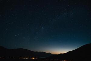 the night sky over a city and mountains photo