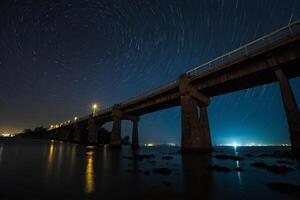 a bridge with star trails over it at night photo