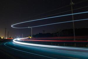 ai generado largo exposición de carros en un autopista a noche foto