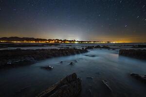 ai generado un largo exposición fotografía de el noche cielo terminado el Oceano foto