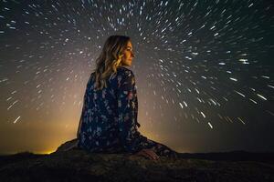 AI generated a woman sitting on a rock looking at the stars photo