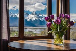 a vase of purple tulips sits on a table in front of a window with mountains in photo