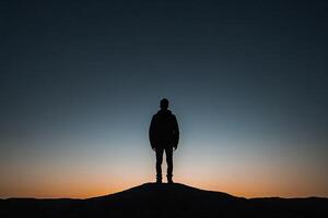 silueta de un hombre en pie en parte superior de un colina a puesta de sol foto