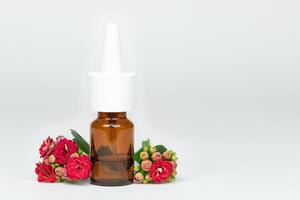 Nasal spray bottle of medicine with red flowers on gray background, allergy photo