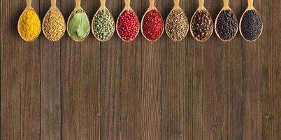 Various spices and herbs in wooden spoons. Condiments on vintage table with empty space for text or label. photo