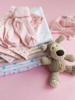 Baby crocketed toy of dog next to a stack rompers for kids photo