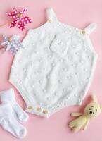 Set of white clothes and accessories for newborn baby. Knitted toys, knitted romper, socks photo