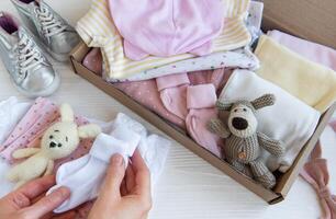 Women's hands collect children's clothes into boxes. photo