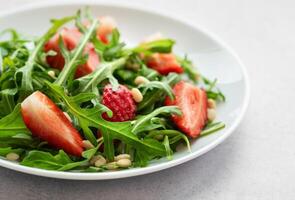 Fresh Strawberry Arugula Salad With Pine Nuts Served on a Bright Day photo
