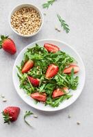 Fresh Strawberry Arugula Salad With Pine Nuts Served on a Bright Day photo